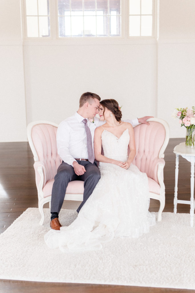 pretty in pink styled shoot bride and groom on sofa